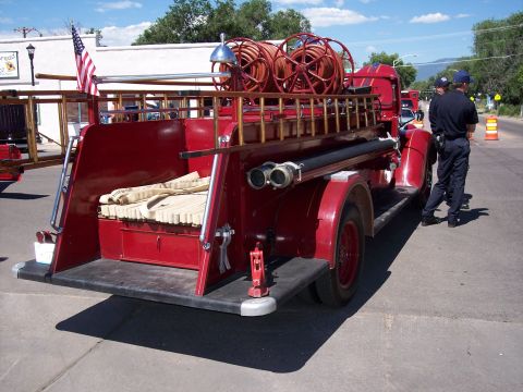 1972 Ford Ranchero - A vintage red fire truck is viewed from the rear, equipped with hoses and ladders, parked on a street.