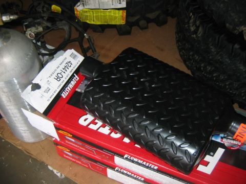 1992 Ford Mustang - A black diamond plate exhaust muffler sits on top of several Flowmaster boxes, with other vehicle parts visible in the background.