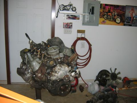 1992 Ford Mustang - Engine assembly on a stand in a garage setting with various tools and posters on the wall.