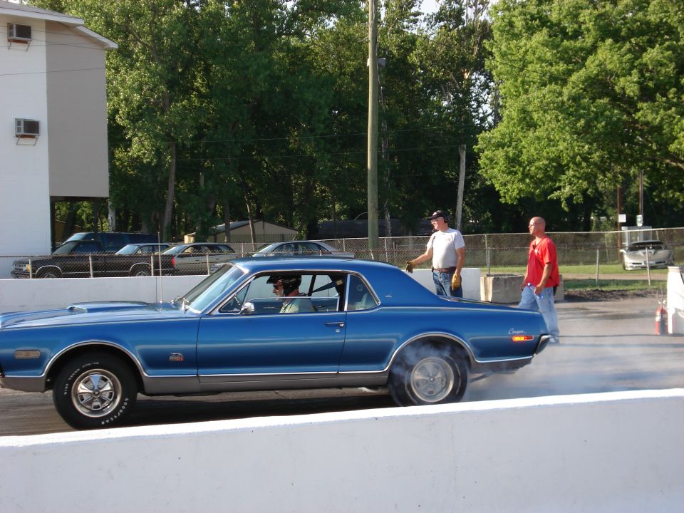 Blue late-1960s Mercury Cougar coupe doing a burnout at a drag strip