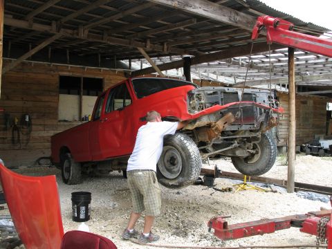 1995 Ford Bronco - A red truck, likely from the early to mid-1990s, is undergoing repairs in a barn-like structure.