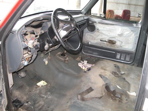 1995 Ford Bronco - The interior of a red 1992 Ford F-150 shows a disassembled dashboard and door panels, indicating it is undergoing repairs or modifications.