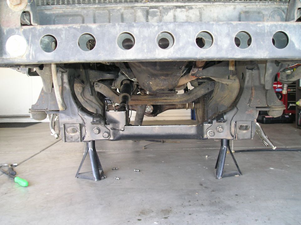 vehicle front suspension on jack stands, showing frame and drivetrain components