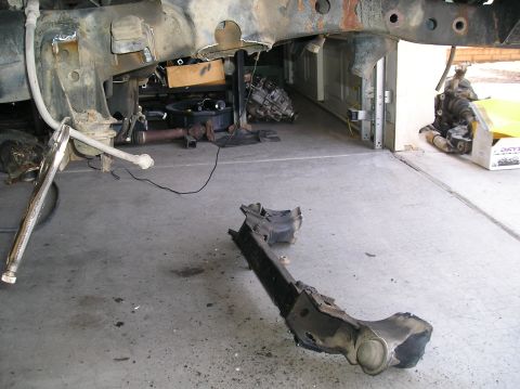 1986 Toyota Hilux - Disassembled vehicle frame and suspension parts are laid out on a garage floor.