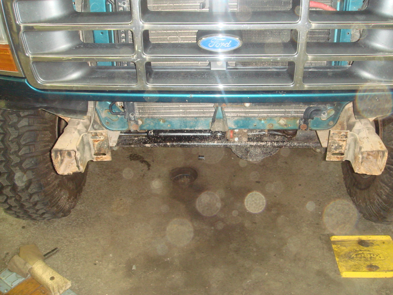 Front of a 1996 Ford Bronco with a Ford emblem on the grille. The vehicle has large tires and appears to be in a garage