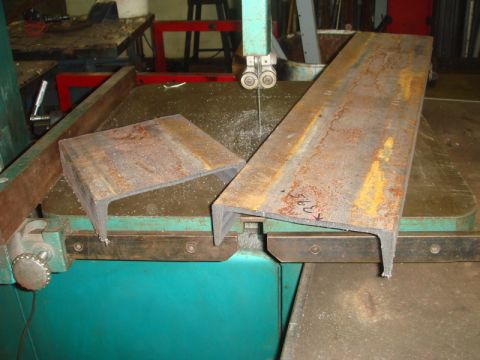 1996 Ford Bronco - Metal pieces are being cut on a band saw in a workshop setting.