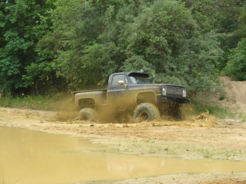 1976 Chevrolet Blazer - This pickup truck is navigating a muddy off-road course, with water and mud splashing around its tires.