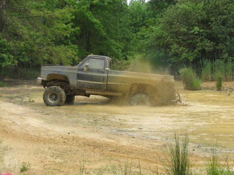 1976 Chevrolet Blazer - This lifted pickup truck kicks up a significant amount of mud as it navigates a wet, off-road course.