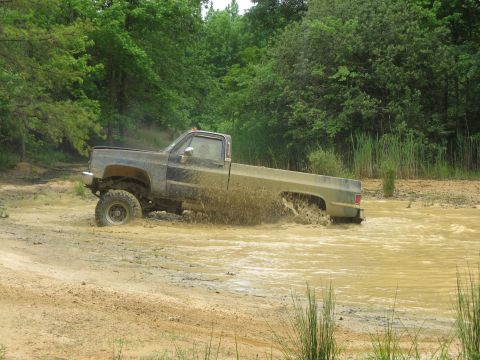 1976 Chevrolet Blazer - This pickup truck is navigating a muddy off-road course, splashing water as it goes.