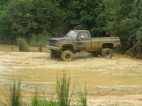 1976 Chevrolet Blazer - This lifted pickup truck is navigating through a muddy off-road course.