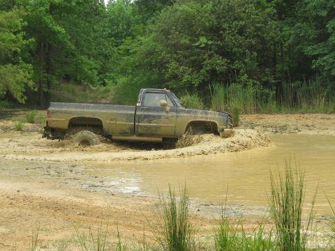 1976 Chevrolet Blazer - This pickup truck is stuck deep in a mud pit, with water splashing around its tires.