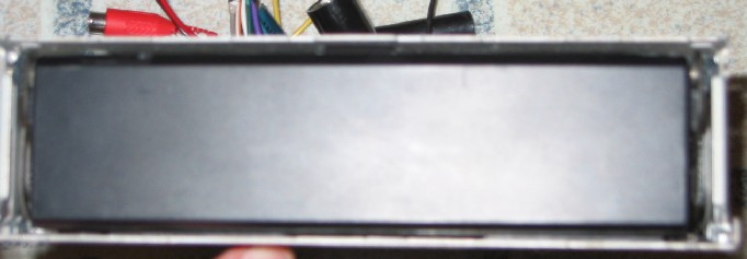 Front of car stereo head unit in metal sleeve with RCA cables and wiring harness behind