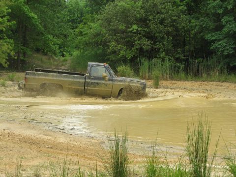 1976 Chevrolet Blazer - Pickup truck struggling through a muddy water obstacle.