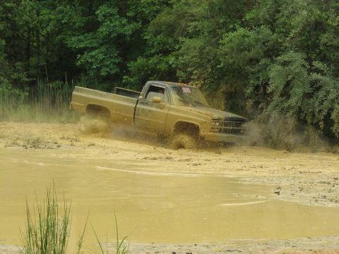 1976 Chevrolet Blazer - Pickup truck navigating a muddy water obstacle.