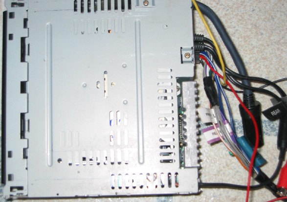 Car stereo head unit chassis from above with color-coded wiring harness and RCA preouts