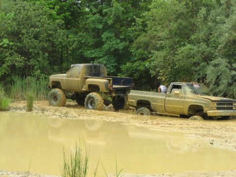 1976 Chevrolet Blazer - Two trucks are stuck in a mud pit, with one truck appearing to be stuck deeper than the other.