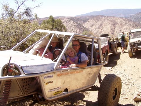 1967 Ford Bronco - Family rides in a custom off-road buggy on a dusty trail, with other vehicles in the background.