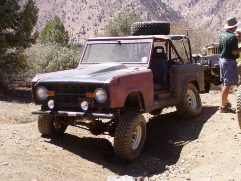 1967 Ford Bronco - A modified Ford Bronco sits on a dusty trail, with another vehicle and people nearby.