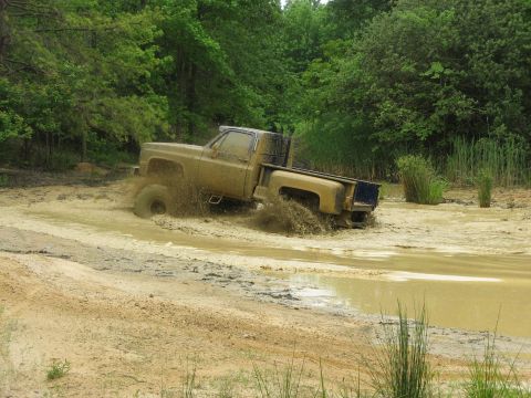 1976 Chevrolet Blazer - This truck is deep in the mud, kicking up a lot of spray as it drives through the water.