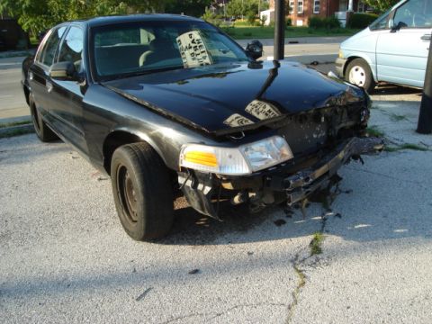 1992 Ford Crown Victoria - This black sedan has significant damage to its front bumper and grille area.