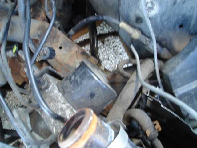 Engine bay with hoses, wires, and rusty metal frame