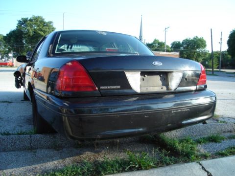1992 Ford Crown Victoria - This black Ford Crown Victoria Police Interceptor is parked with its front wheel elevated on a curb.