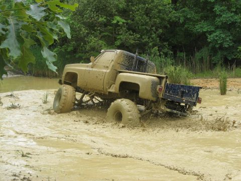 1976 Chevrolet Blazer - This lifted pickup truck is deep in the mud, showing its rear end as it struggles to move.