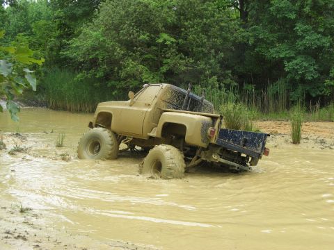 1976 Chevrolet Blazer - This lifted pickup truck is deep in the mud, with only its tires and part of the body visible above the murky water.