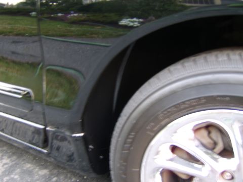 1996 Mercury Grand Marquis - A close-up view of a vehicle's wheel well and tire, showing chrome trim on the door panel.
