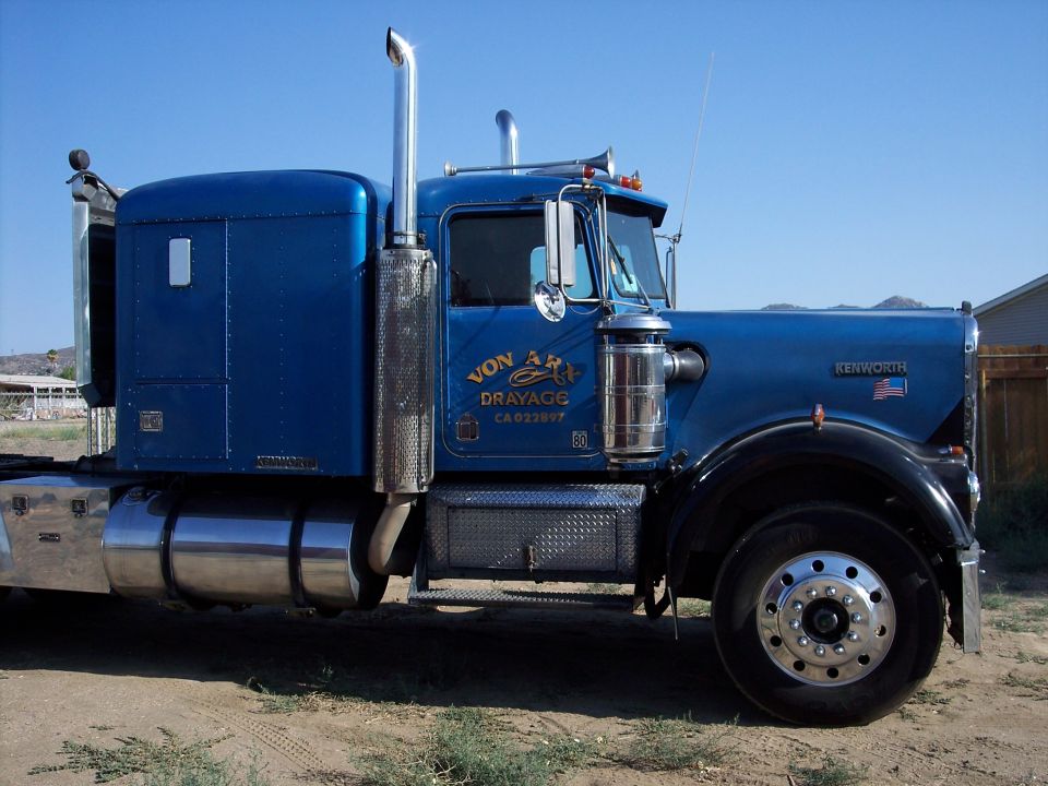 Blue Kenworth sleeper-cab semi truck, side view, with chrome stack and Von Ary Drayage door lettering