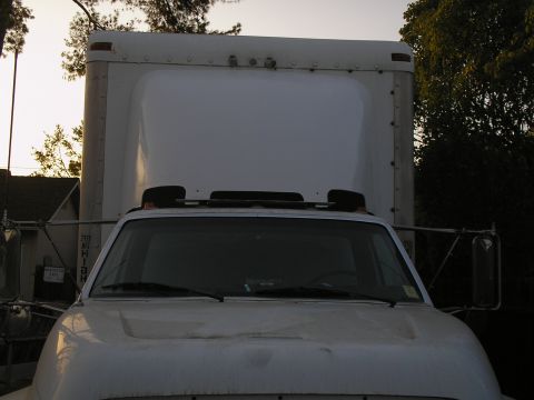 1999 Ford F-800 - This box truck is parked outside with trees and a house in the background. The sky is clear.