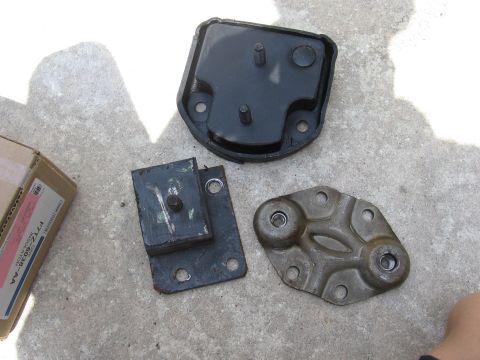 1974 Ford F-100 - Engine mounts and a box are laid out on concrete, with visible text on the box and a watermark at the bottom right.