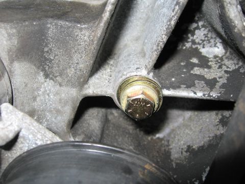 1974 Ford F-100 - A close-up view of a bolt on a metal engine component, with a black pulley in the foreground.