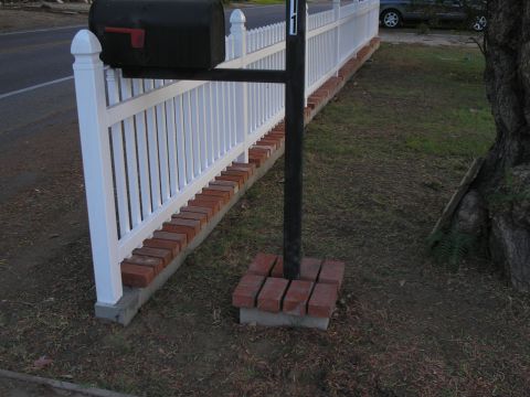 1990 Ford Bronco - A dark sedan is visible parked behind a white picket fence next to a mailbox.