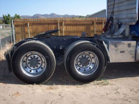 1981 Kenworth W900A - Side view of a truck's rear dual wheels and axles, with a metal toolbox mounted on the side.