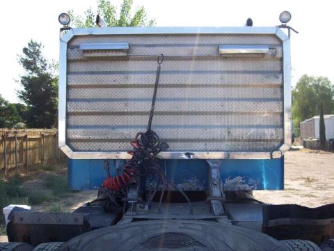 1981 Kenworth W900A - The rear of a semi-trailer truck, showing its diamond plate and blue body with attached air hoses.