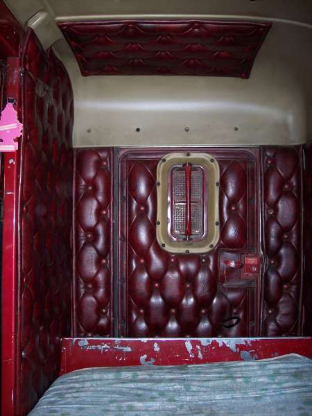 1981 Kenworth W900A - Interior view of a truck's sleeper cab, showing red tufted upholstery and a bed.