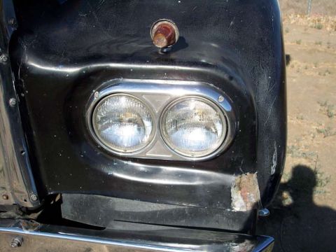 1981 Kenworth W900A - Close-up of a black truck's front fender, showing dual headlights and chrome accents. The fender has visible damage on the right side.