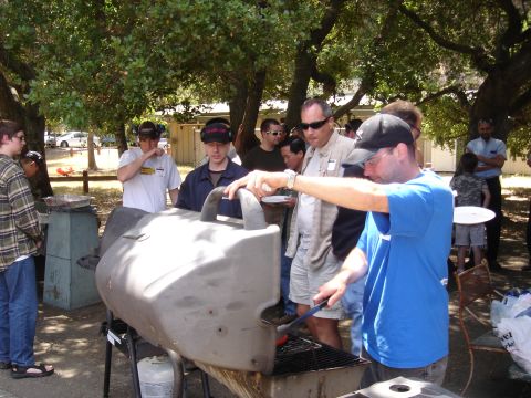 1990 Ford Bronco - An outdoor gathering with several people around a large barbecue grill, some preparing food.