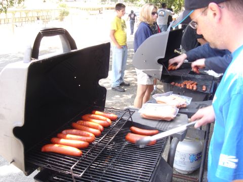 1990 Ford Bronco - Several people are gathered around outdoor grills, cooking hot dogs on a sunny day.