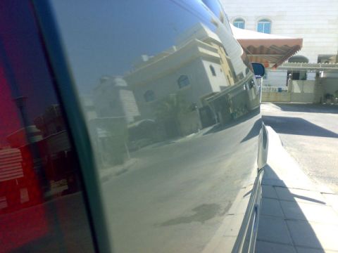 2007 Mercury Grand Marquis - The side of a vehicle reflects buildings and a street under a bright sky.