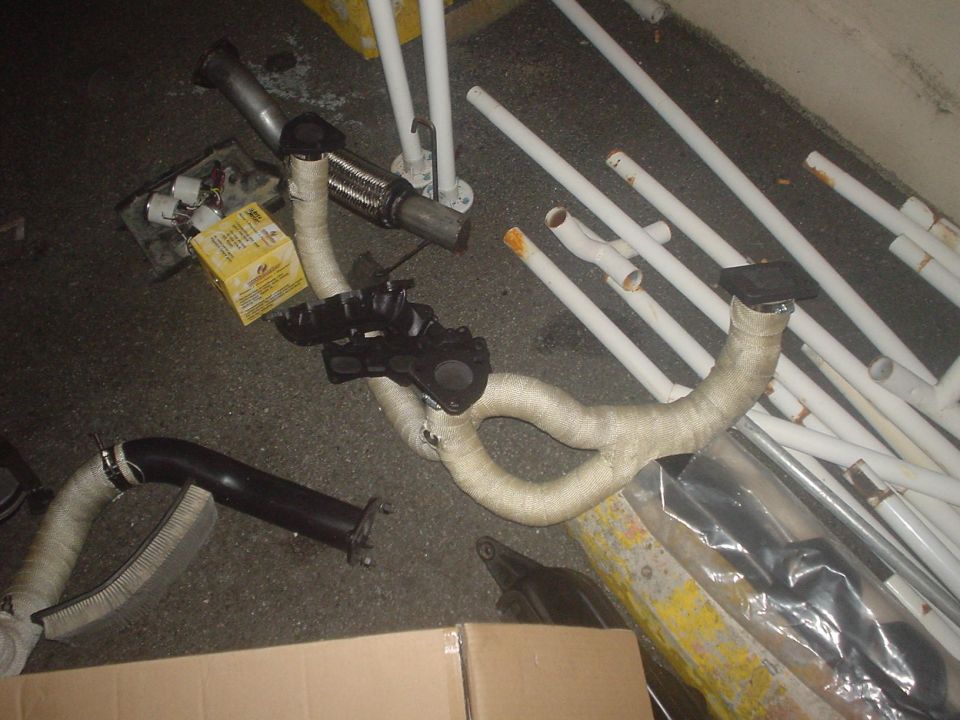 Heat-wrapped exhaust headers and pipes laid out on a garage floor