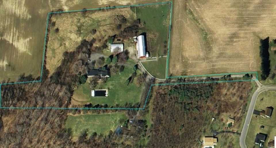 Aerial view of a farm property with a house, barn, outbuildings, and a swimming pool