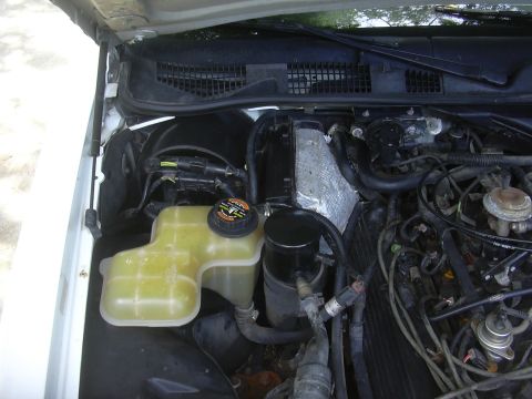 1997 Ford Crown Victoria - Close-up view of a vehicle's engine bay, showing the coolant reservoir and other components.