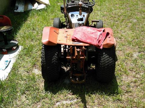 1986 Ford Bronco - Lawn tractor with a red towel draped over the seat, parked on grass.