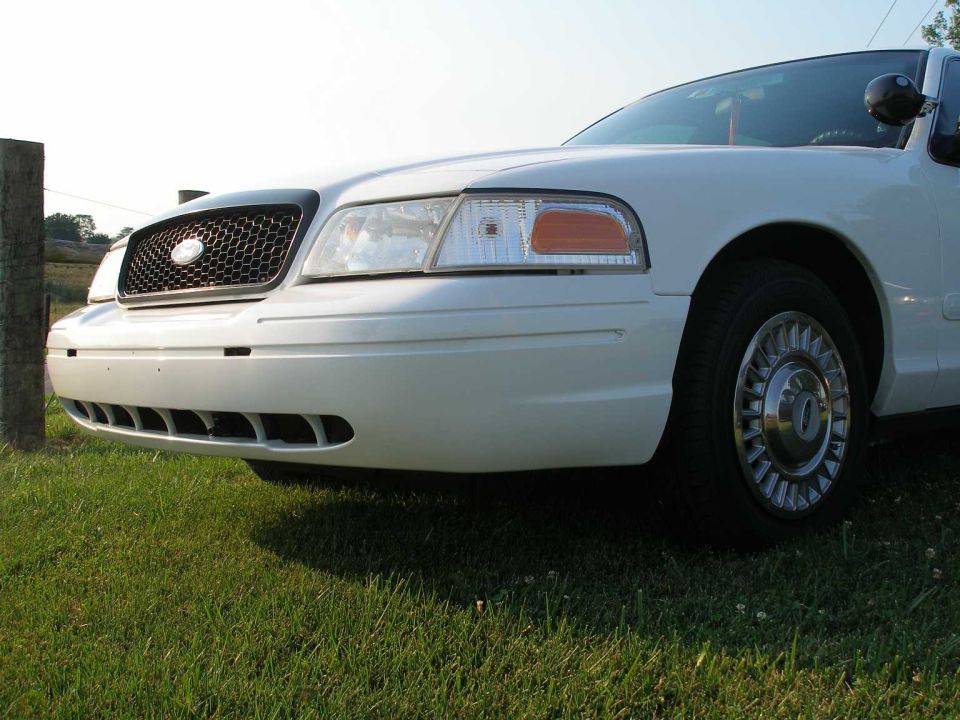 White 2001 Ford Crown Victoria front grille and headlight, parked on grass