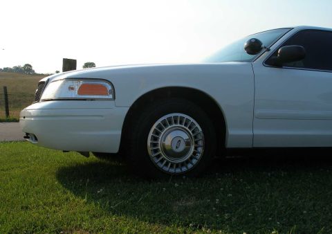 2001 Ford Crown Victoria - A white 2001 Ford Crown Victoria is seen from the front quarter angle, parked on a grassy area.