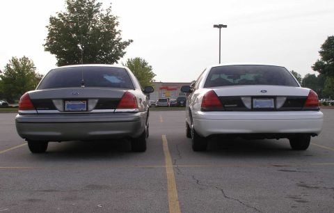 2001 Ford Crown Victoria - Two 2001 Ford Crown Victorias are parked in a lot, viewed from the rear.