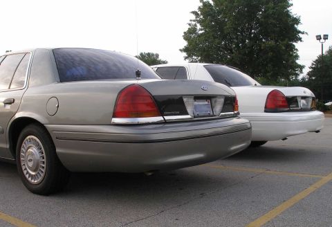 2001 Ford Crown Victoria - Two Ford Crown Victorias are parked side-by-side, showing their rear ends.