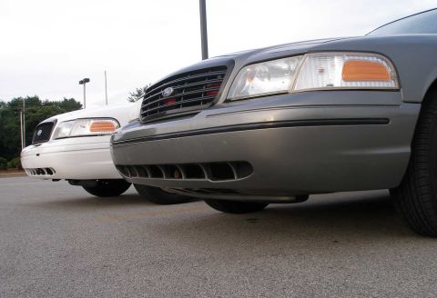 2001 Ford Crown Victoria - Two Ford Crown Victorias are parked next to each other, showing their front ends.